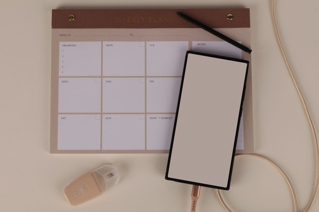 A weekly planner with phone and stationery.